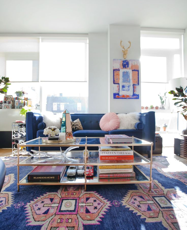 Maximalist interior design trend room with large rug, statement artwork and a crowded coffee table with books