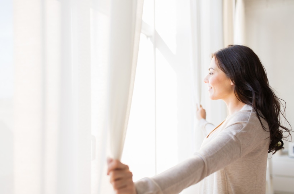 Woman opening curtains hung from ceiling